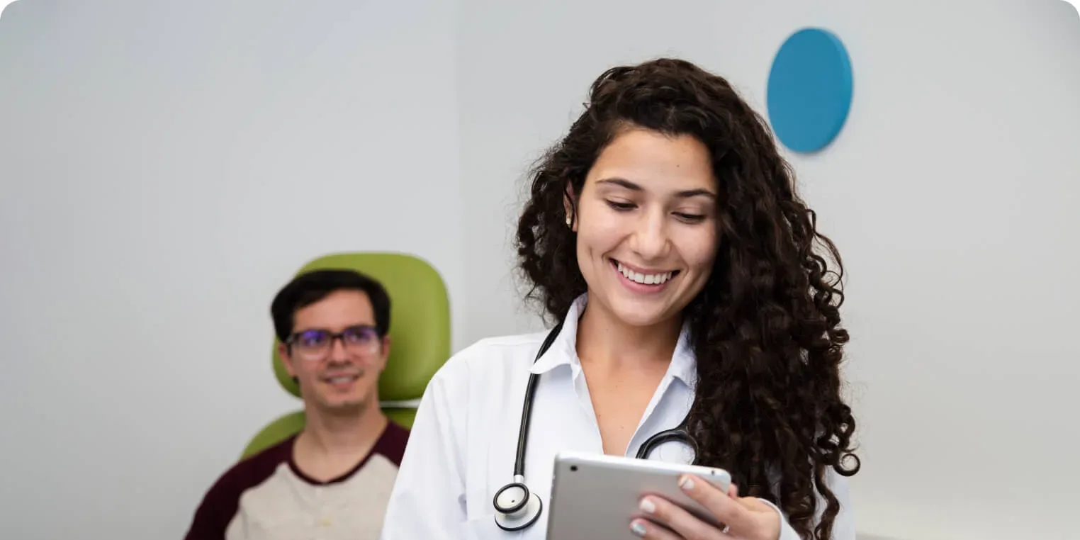 A doctor with a tablet, and a patient waiting behind her